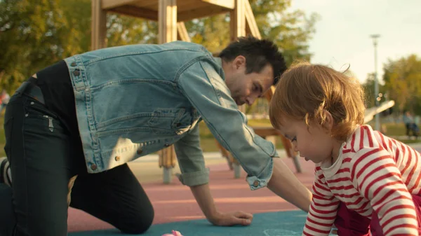 Mann zeichnet mit Kreide auf Spielplatz — Stockfoto