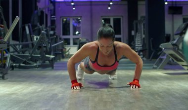 Kadın vücut geliştirmeci itme yapıyor. Spor salonunda atlet.