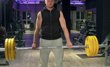 Atletik adam büyük çanı kaldırıyor. Spor salonunda atlet.