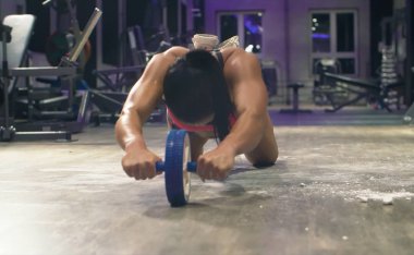 Atletik kadın ab tekerlek egzersizleri yapıyor. Vücut geliştirme konsepti.