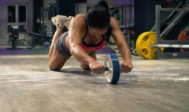 Atletik kadın ab tekerlek egzersizleri yapıyor. Vücut geliştirme konsepti.