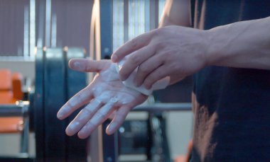 Vücut geliştirmeci ellerini tebeşirle. Antrenmanın başlaması