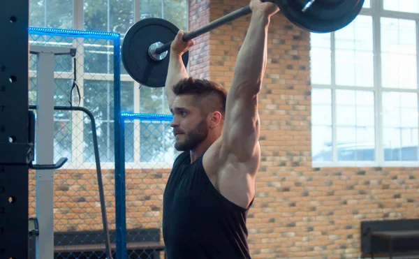 El atleta masculino levantando la barra en el gimnasio — Foto de Stock