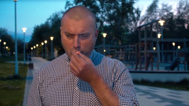 Портрет агрессивного жестокого человека, курящего в парке — стоковое видео