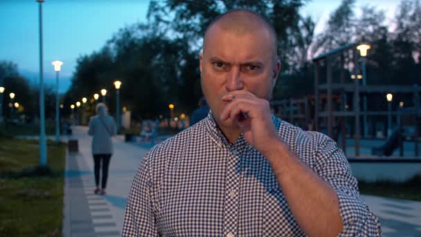 Porträt eines aggressiven brutalen Mannes, der im Park raucht — Stockvideo