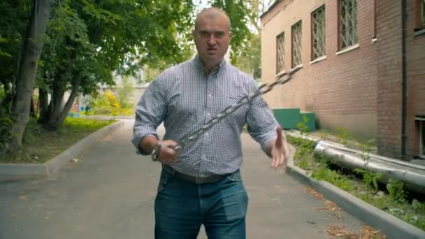 Agressieve offensieve man met een ketting in zijn handen — Stockvideo