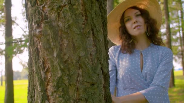 Молода приваблива жінка стоїть біля дерева — стокове відео