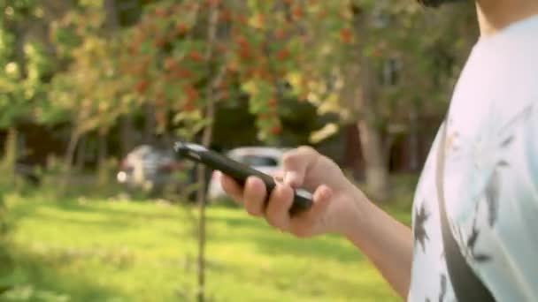 Ruka muže při chůzi a posouvání inteligentního telefonu — Stock video