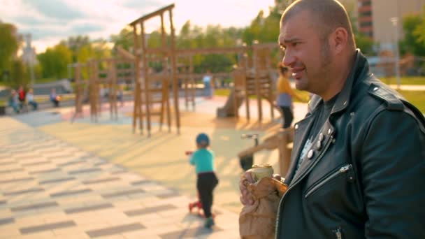 Retrato de um homem brutal a beber cerveja ilegalmente no parque infantil — Vídeo de Stock