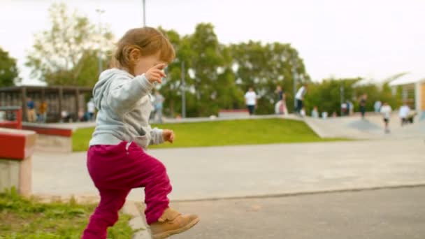 Маленькая девочка гуляла рядом с скейт-парком — стоковое видео