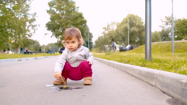 小さな水たまりで花を浴ぶ女の赤ちゃん — ストック動画