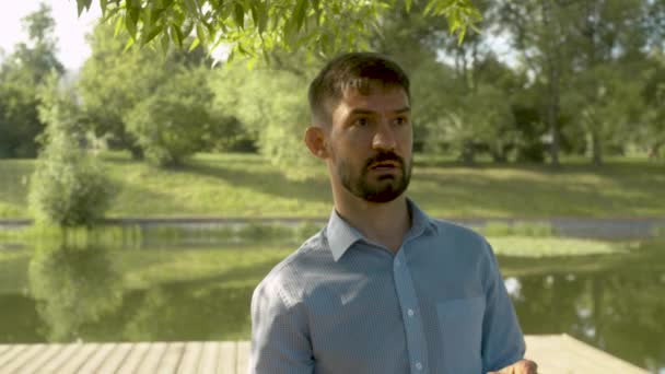 Retrato de um homem contra lago e parque — Vídeo de Stock