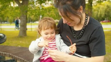 Anne dizlerinin üzerinde oynayan kız bebek