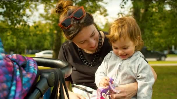 Lustiges kleines Mädchen sitzt auf Mamas Knien — Stockvideo