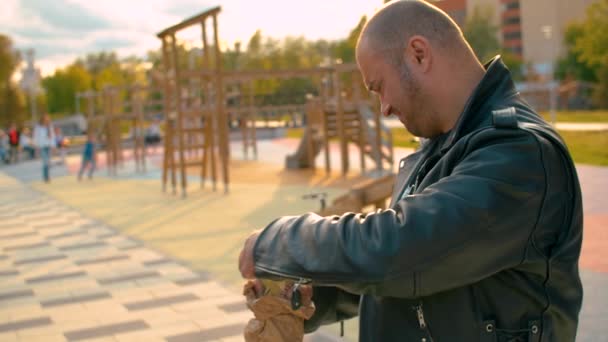 Portrait of a brutal man illegally drinking beer on the kids playground — Stock Video