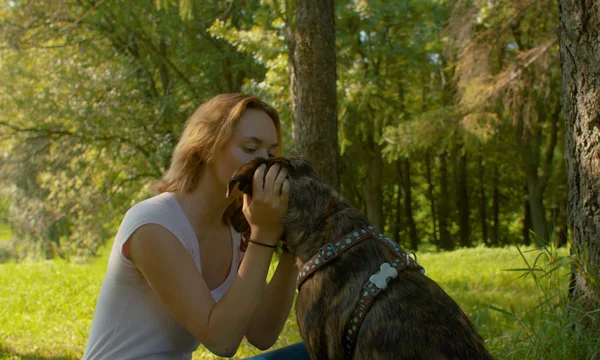 Atractiva mujer sonriente besando a su buen perro — Foto de Stock