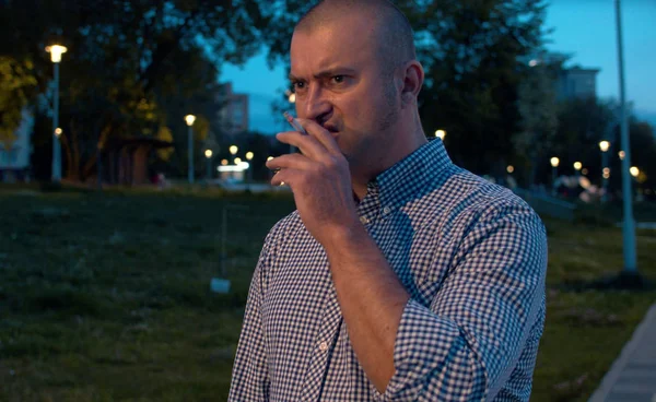 Портрет агрессивного жестокого человека, курящего в парке — стоковое фото