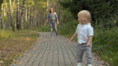 Küçük çocuk parkta yol boyunca yürüyor.