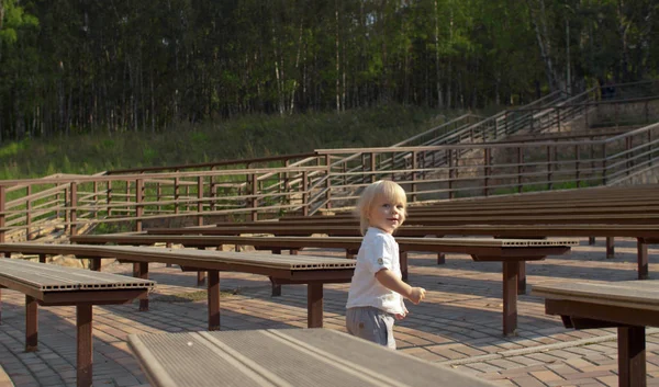 Chlapec kráčí mezi lavicemi — Stock fotografie