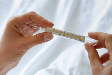 Kadının eli termometreyi tutuyor.