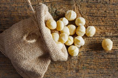 Tahta arka planda küçük çuvalda Macadamia fındıkları