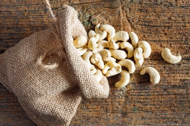 Tahta arka planda küçük çuvalda kaju fıstığı.