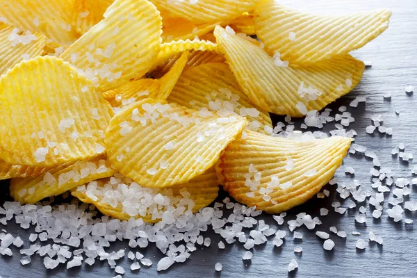 Salt in food - potato chips and salt. Unhealthy food concept