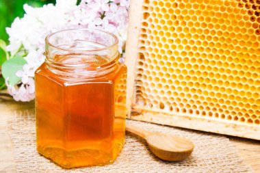 Bal küçük kavanozda, bal peteği ve çiçek arka planda