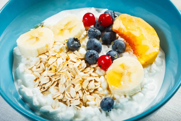 Sağlıklı kahvaltı. Granüle edilmiş süzme peynir artı yulaf gevreği, muz, yabanmersini, frenk üzümü, şeftali ve bal..