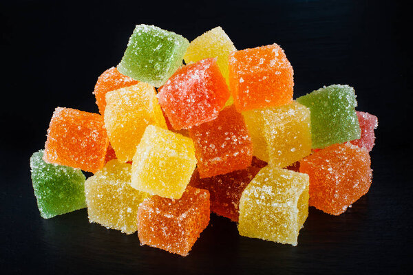 Sugar coated, sweet colorful jelly cubes on black slate board