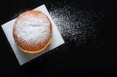 Koyu arkaplanda çörek ve pudra şekeri.