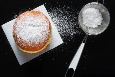 Koyu arkaplanda çörek ve pudra şekeri.