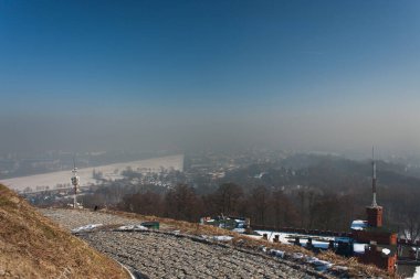 CRACOW, POLAND - JANUARY 30, 2017. Smog over city - unclear view from Kosciuszko Mound in the direction of the Wawel Castle and old town. Smog is a kind of air pollution occurring very often in Cracow clipart