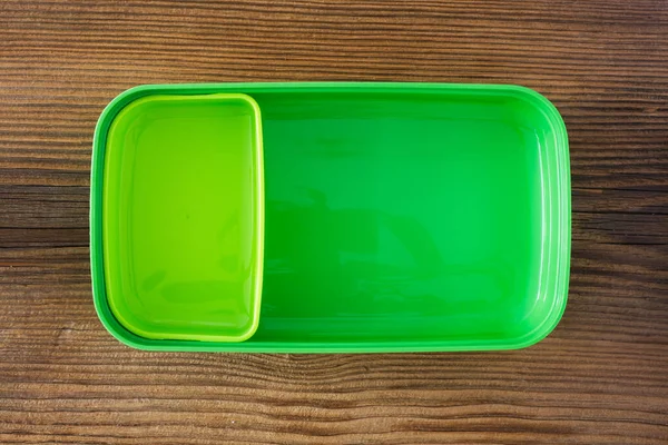 Ahşap arka planda yeşil plastik beslenme çantası