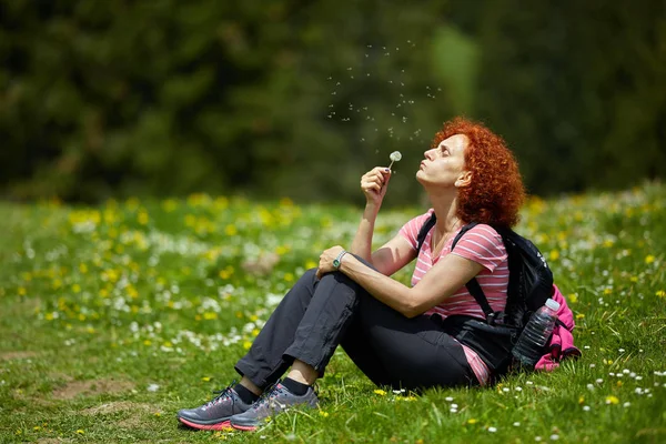 Mujer Excursionista Descansando Hierba Soplando Dientes León — Foto de Stock