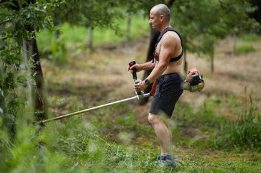 Adam ile bir brushcutter, biçme makinesi motorlu kara biçme