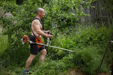 Adam ile bir brushcutter, biçme makinesi motorlu kara biçme
