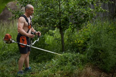 Adam ile bir brushcutter, biçme makinesi motorlu kara biçme