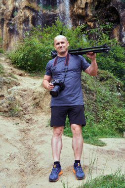 Kamera ve arka plan üzerinde şelale ile profesyonel fotoğrafçı