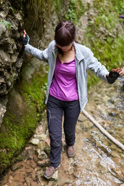 横跨河的年轻妇女徒步旅行者峡谷 — 图库照片