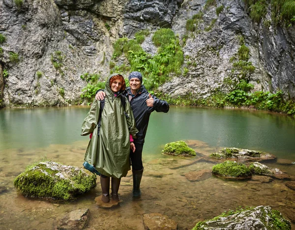 レインコートの湧水によってポーズのカップル — ストック写真