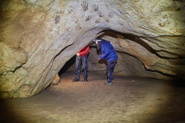 一对年轻的徒步旅行者在石灰岩山脉探索洞穴 — 图库照片