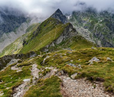 Dağlık arazide, sisli dağlarda yürüyüş izleri var.