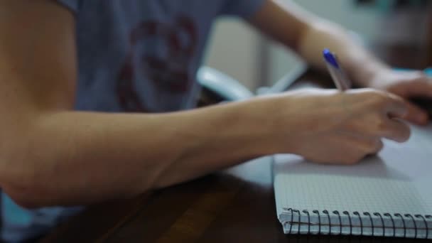 Gros plan de l'élève de l'école masculine écrivant ses devoirs dans un copybook 