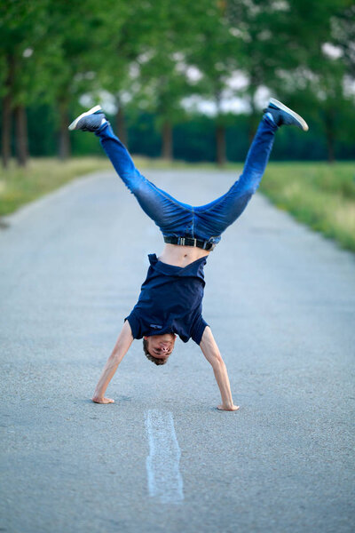 Young boy walking on hands in the middle of the road