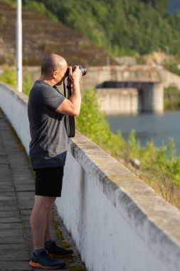 Orta yaşlı erkek fotoğrafçı ile gündüz açık fotoğraf çekmeye profesyonel fotoğraf makinesi