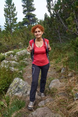 Orta yaşlı kadın gündüz dağlarda izinde hiking sırt çantası ile