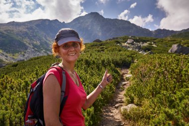 Orta yaşlı kadın gündüz dağlarda izinde hiking sırt çantası ile