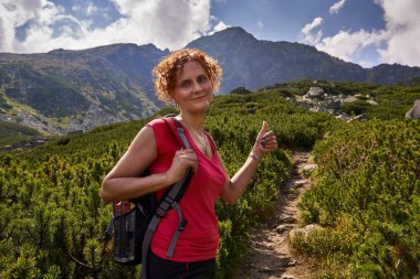 Orta yaşlı kadın gündüz dağlarda izinde hiking sırt çantası ile