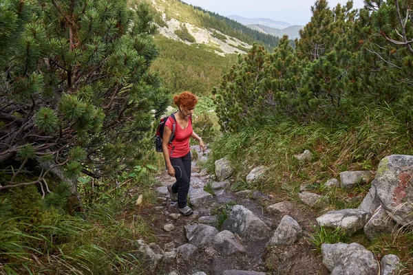 中年女性の昼間の山の道でハイキングのバックパック — ストック写真